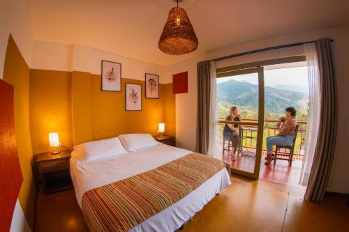 Un dormitorio con una cama y un balcón con una mujer en Viajero Salento Hostel, en Salento