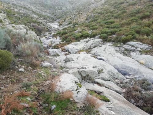 a mountain with rocks and a stream of water at CASA GORDON in Navaluenga