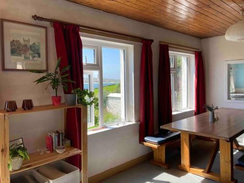 Habitación con mesa y ventanas con cortinas rojas. en Cosy Stay on The Wild Atlantic Way, en Malin