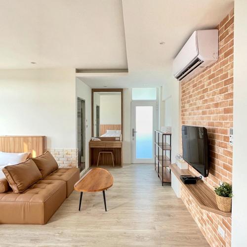 a living room with a couch and a tv at Pomelo Homestay in Houli