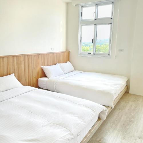 two beds in a room with a window at Pomelo Homestay in Houli