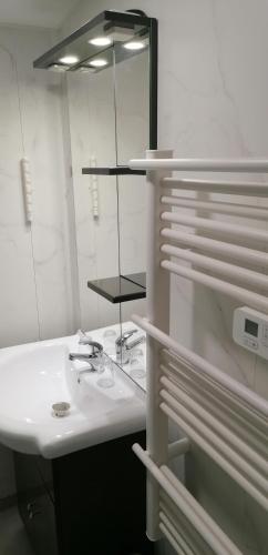 a white bathroom with a sink and a mirror at GITE DOUSTRET in Argentat