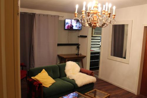 sala de estar con sofá verde y lámpara de araña en Apartment Rainer, en Heddesheim