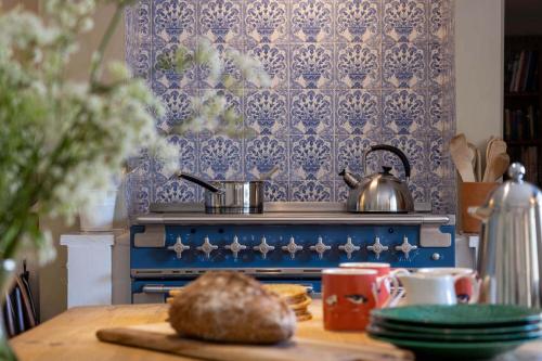 a kitchen with a blue stove with a tea pot on it at Thatched Hat Cottage in Lymington