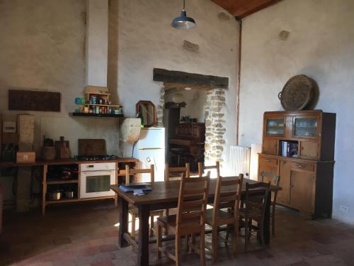 une cuisine avec une table et des chaises dans une pièce dans l'établissement Jolie maison ancienne adaptée aux petits groupes - Maison Peyri, à Léogeats