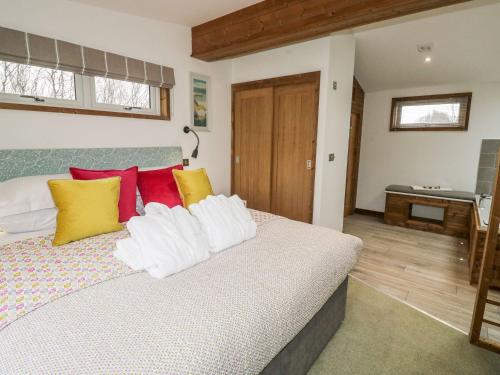 a bedroom with a bed with colorful pillows at 2 Meadow Retreat in Liskeard