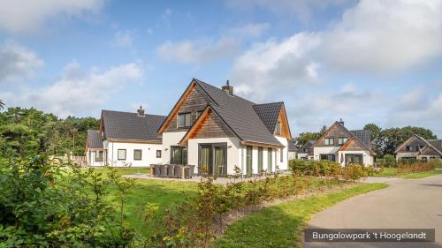 a white house with a black roof at Bungalowpark 't Hoogelandt in De Koog