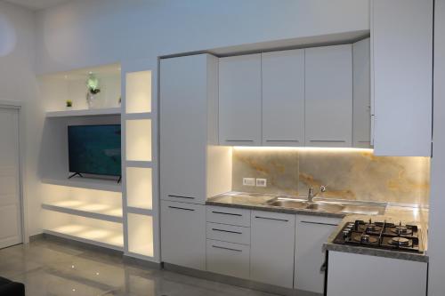 拿坡里的住宿－Barbaro Apartment Centro di Napoli，一间带白色橱柜和水槽的厨房以及一台电视。