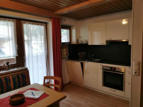 une cuisine avec des placards blancs, une table et une fenêtre dans l'établissement Haus Martha, à Kaunertal