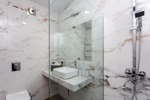 a bathroom with a sink and a glass shower at New Saburtalo Apartment in Tbilisi City