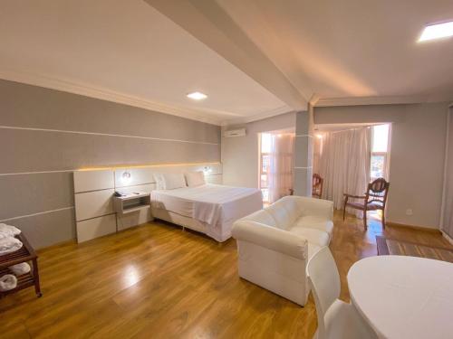 a bedroom with a bed and a couch and a table at Hotel Verde Plaza in Santana do Livramento