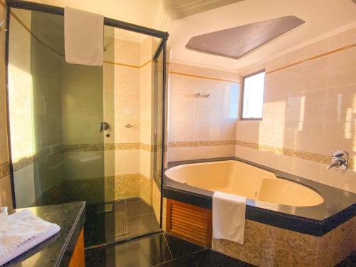 y baño con bañera, ducha y lavamanos. en Hotel Verde Plaza, en Santana do Livramento