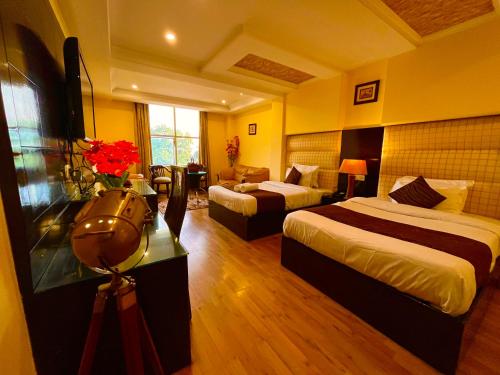 a hotel room with two beds and a table with flowers at Reo Resort, near bus stand & railway station ,Haridwar in Haridwār