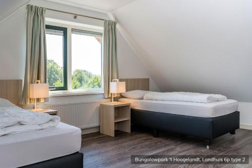 two beds in a room with two windows at Bungalowpark 't Hoogelandt in De Koog
