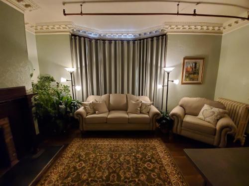 a living room with two couches in front of a curtain at Daniell Manor in Laurium