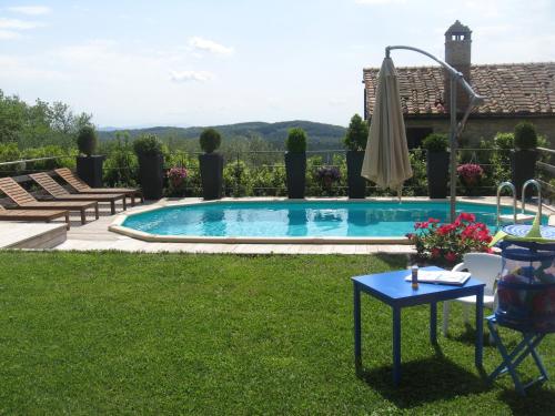 a swimming pool in a yard with a table and an umbrella at Casale La Petrosa in Radda in Chianti