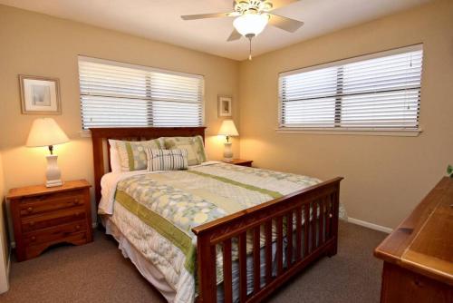 a bedroom with a bed and two windows and a ceiling fan at Comal River Bliss in New Braunfels
