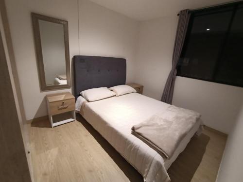 a small bedroom with a bed and a mirror at Apartamento en zona norte bogota in Bogotá