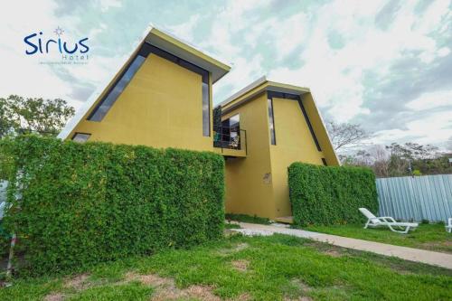 a yellow house with a hedge in front of it at Hotel Sirius Costa Rica in San Mateo