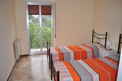 two beds in a room with a window at Casa Catena in Francavilla di Sicilia