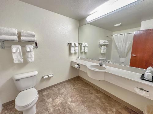 a bathroom with a toilet and a sink and a mirror at Estherville Hotel & Suites in Estherville
