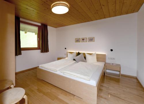 Schlafzimmer mit einem großen weißen Bett und einer Holzdecke in der Unterkunft Ferienwohnungen Lingg in Schoppernau