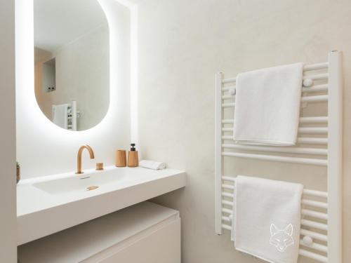 een witte badkamer met een wastafel en een spiegel bij Tiny Fox Kluisbos in Orlitain