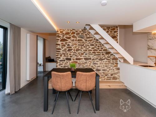 a dining room with a stone wall and a table and chairs at Tiny Fox Kluisbos in Mont-de-l'Enclus