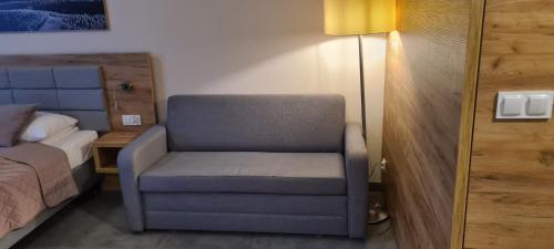 a bedroom with a chair and a bed and a lamp at Aparthotel Apartamenty Czarna Góra 310 in Sienna