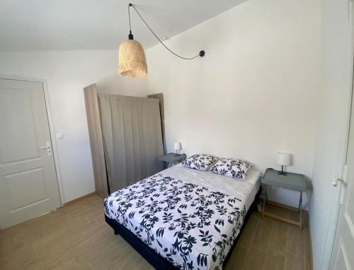 a bedroom with a bed with a black and white comforter at Paisible maisonnette à Entraigues sur la Sorgue in Entraigues-sur-la-Sorgue