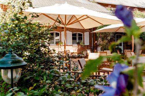 a patio with tables and chairs and an umbrella at Meyers in Isenbüttel