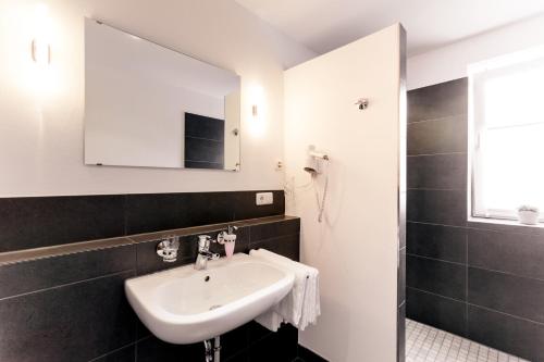 ein Bad mit einem Waschbecken und einem Spiegel in der Unterkunft Meyers Hofcafe in Isenbüttel