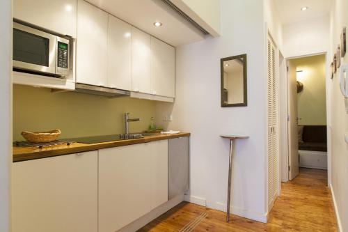 uma cozinha com armários brancos e um micro-ondas em Chic 1-bed flat with balcony, view and workspace, 5mins to Santa Justa Lift em Lisboa