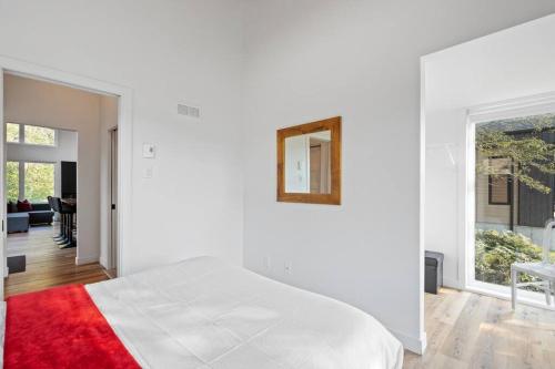 a white bedroom with a white bed and a red rug at Initial / Mano / MSA in Saint-Férréol-les-Neiges
