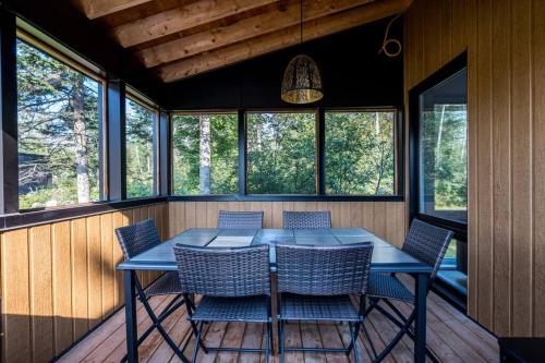 a table and chairs in a screened in porch with windows at Initial / Mano / MSA in Saint-Férréol-les-Neiges