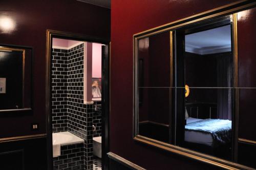 a bathroom with a mirror and a room with a bed at Alba Opéra Hôtel in Paris