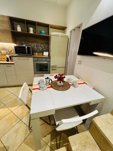 a kitchen with a white table with chairs and a refrigerator at Casa dei fiori in Carovigno