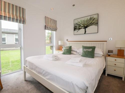 a bedroom with a large white bed with green pillows at 9 Horizon View in Liskeard