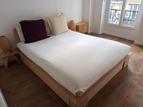 Cette chambre comprend un grand lit avec des draps et des oreillers blancs. dans l'établissement APPARTEMENT SACRE COEUR, à Paris