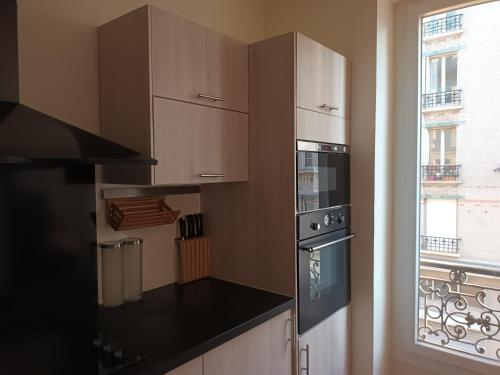 une cuisine avec des armoires blanches et un comptoir noir dans l'établissement APPARTEMENT SACRE COEUR, à Paris