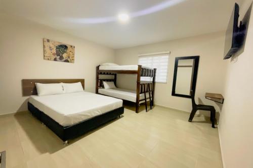a bedroom with a bed and a bunk bed and a chair at Hotel Andina Blue Santa Marta in Santa Marta