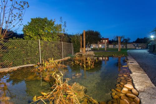 a pond with a fence and some plants in it at Casa de Campo Sossego da Lata in Fafe