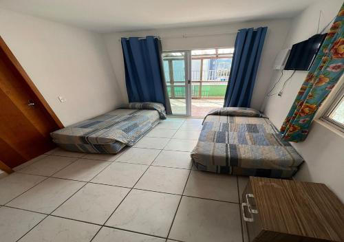 dwa łóżka w pokoju z oknem w obiekcie Residencial Louise w mieście Balneário Camboriú