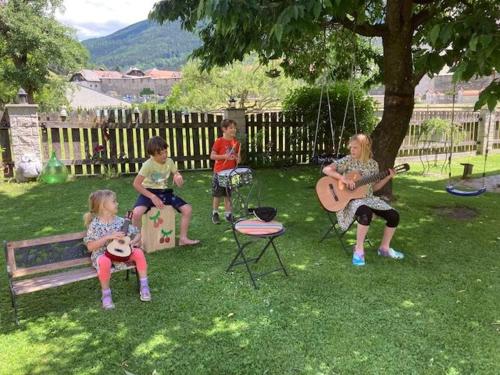 a group of children sitting on a bench in a yard at Pension & Ferienwohnung Dullnig in Gmünd in Kärnten