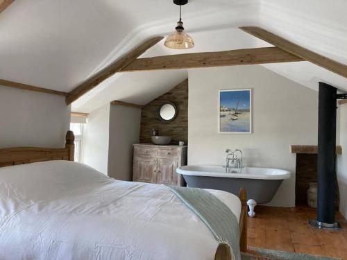 1 dormitorio con cama y bañera en Restored, beautiful cottage, North Cornwall, en Delabole