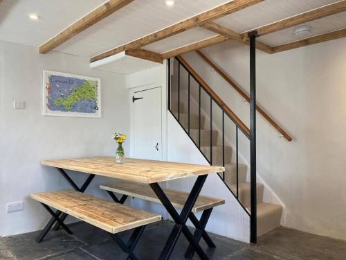 una mesa y bancos en una habitación con escalera en Restored, beautiful cottage, North Cornwall, en Delabole