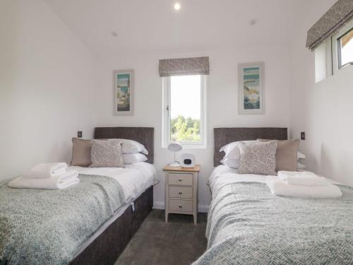 a bedroom with two beds and a window at 7 Meadow Retreat in Liskeard