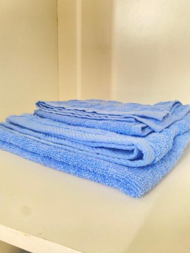 stos niebieskich ręczników na półce w obiekcie Best Rooms- Quarto 4 Plateau w mieście Praia