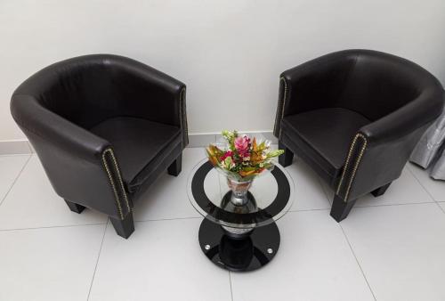 two black chairs and a table with a vase of flowers at Villa (Duplex)JIREH Ablogamé in Ablogamé
