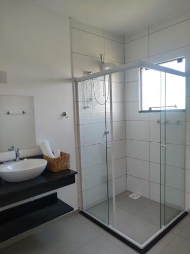 a bathroom with a glass shower and a sink at Bella Ciao Hospedaria in Passo de Torres